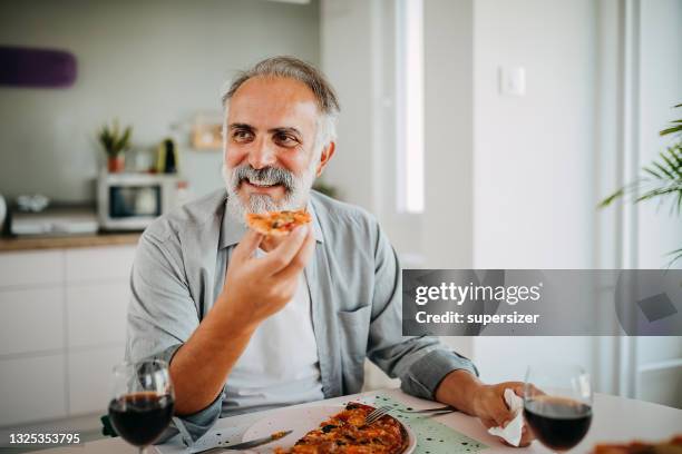 hombre adulto medio comiendo pizza - mid adult men fotografías e imágenes de stock