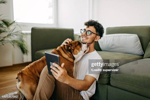 junger mann spielt mit seinem hund - couch hund stock-fotos und bilder