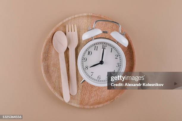 alarm clock on wooden plate with cutlery. concept of intermittent fasting, diet and weight loss. flat lay - fasting stock pictures, royalty-free photos & images