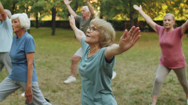 Elderly People Having Outdoor Yoga Workout with Female Instructor