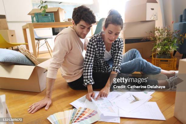 a young couple looking at plans of their new home - young couple moving house stock pictures, royalty-free photos & images