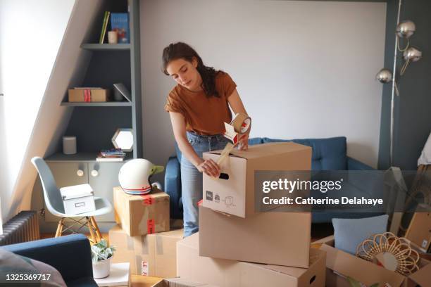 a young woman is packing her moving boxes - 盒 個照片及圖片檔
