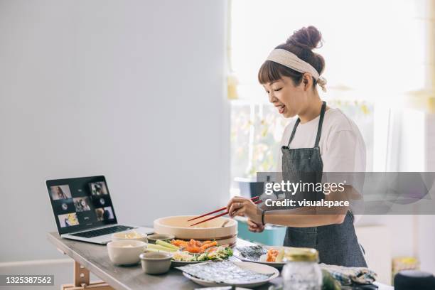 frau kocht essen während eines videoanrufs - woman portrait kitchen laptop stock-fotos und bilder