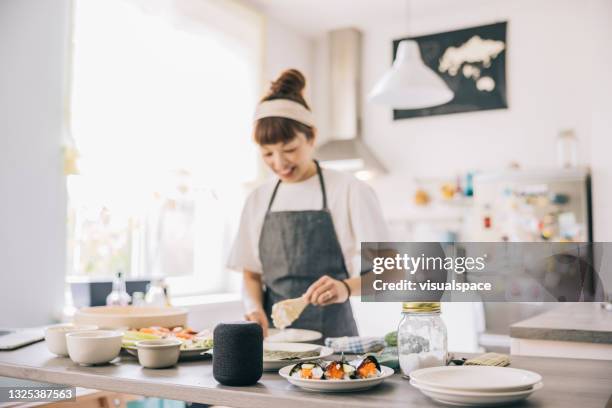 woman using virtual assistant while cooking - coluna inteligente imagens e fotografias de stock