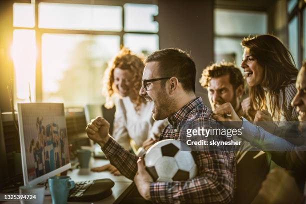 allegri programmatori tifano mentre guardano la loro squadra sportiva su pc in ufficio. - campionato mondiale di sport foto e immagini stock