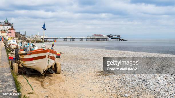 tractors line the edge of cromer beach - cromer pier stock pictures, royalty-free photos & images