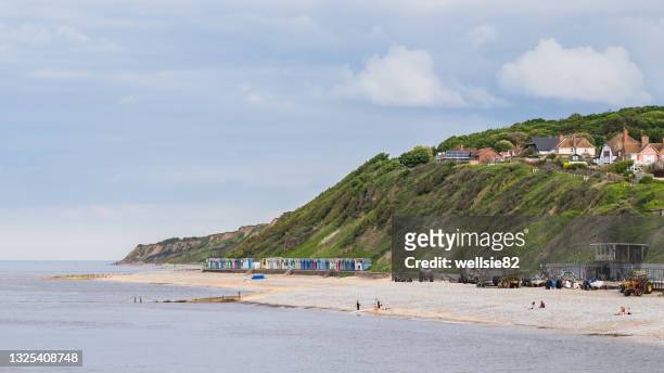 beach huts sandwiched between the sea and cliffs at cromer - east anglia imagens e fotografias de stock