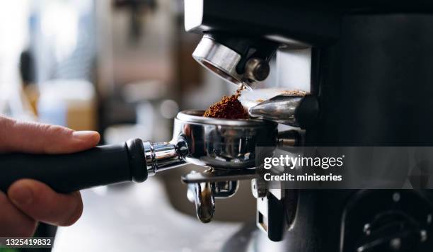 professional grinding freshly roasted coffee in a espresso machine - malen stockfoto's en -beelden