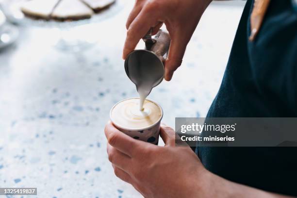 anonymous barista pouring frothed milk in a take away paper cup of coffee - barista coffee milk stock pictures, royalty-free photos & images