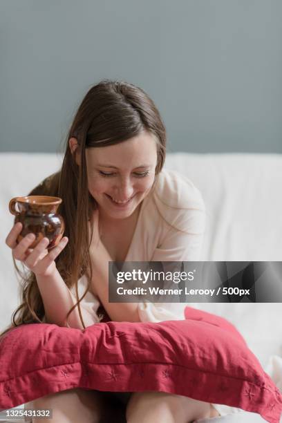 young woman having drink while sitting on bed at home,laken,brussel,belgium - laeken stock-fotos und bilder