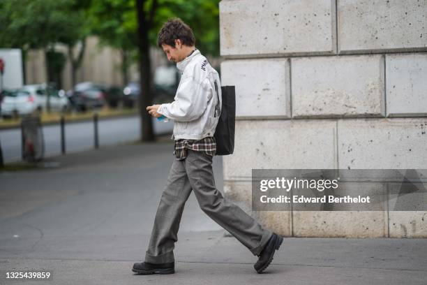 Guest wears a white / pale gray denim jacket with black print pattern on the back, brown beige and yellow checkered long shirt, a black tote-bag /...