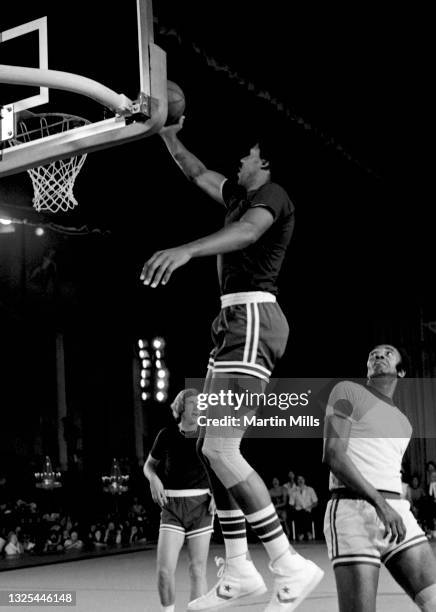 Player of the Philadelphia 76ers Julius Erving goes for the lay-up as former NBA players Sam Jones and Kevin Loughery look on during the 3 on 3...