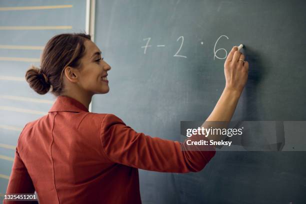 insegnante che scrive un problema di matematica alla lavagna. - insegnante lavagna foto e immagini stock