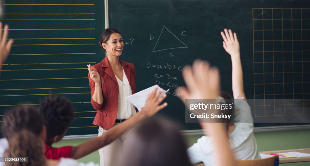 Teacher in front of her class, asking questions.