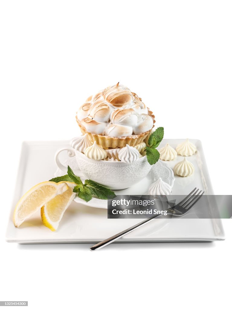 Food photography of shortcrust pastry tartlet with lemon curd side view, decorated with burnt meringue and sugar syrup on a white background isolated close up