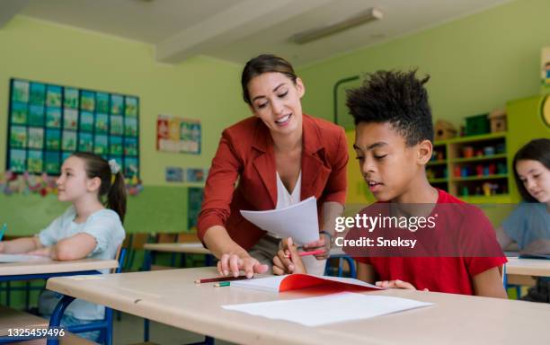 pupil finishing schoolwork. teacher is helping. - student support stock pictures, royalty-free photos & images