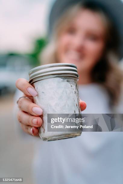 close-up shot of a young happy caucasian woman holding a glass mason jar of lavender sugar at a local small business farm-to-table supplier in colorado - sugar jar stock pictures, royalty-free photos & images