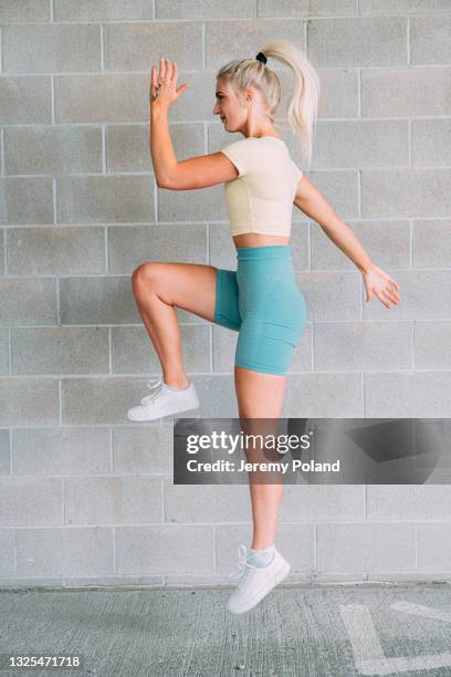 blond caucasian woman in active wear clothing exercising and jumping from a lunge position - hip hopper stock pictures, royalty-free photos & images