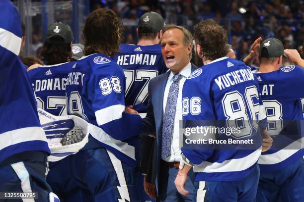 Head coach Jon Cooper of the Tampa Bay Lightning celebrates with Mikhail Sergachev and Nikita Kucherov after defeating the New York Islanders 1-0 in...