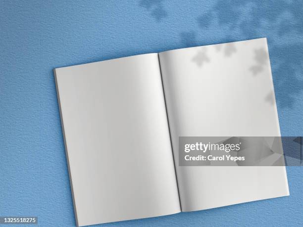 blank magazine page. workspace with magazine mock up on  blue surface - buch tisch stock-fotos und bilder