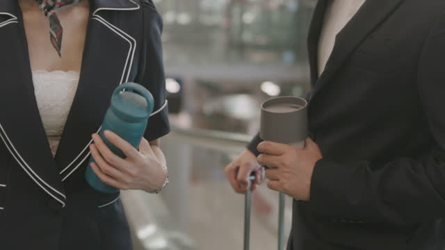 Two Environmentalist flight attendant hold their own private travel mug for flying - stock video
