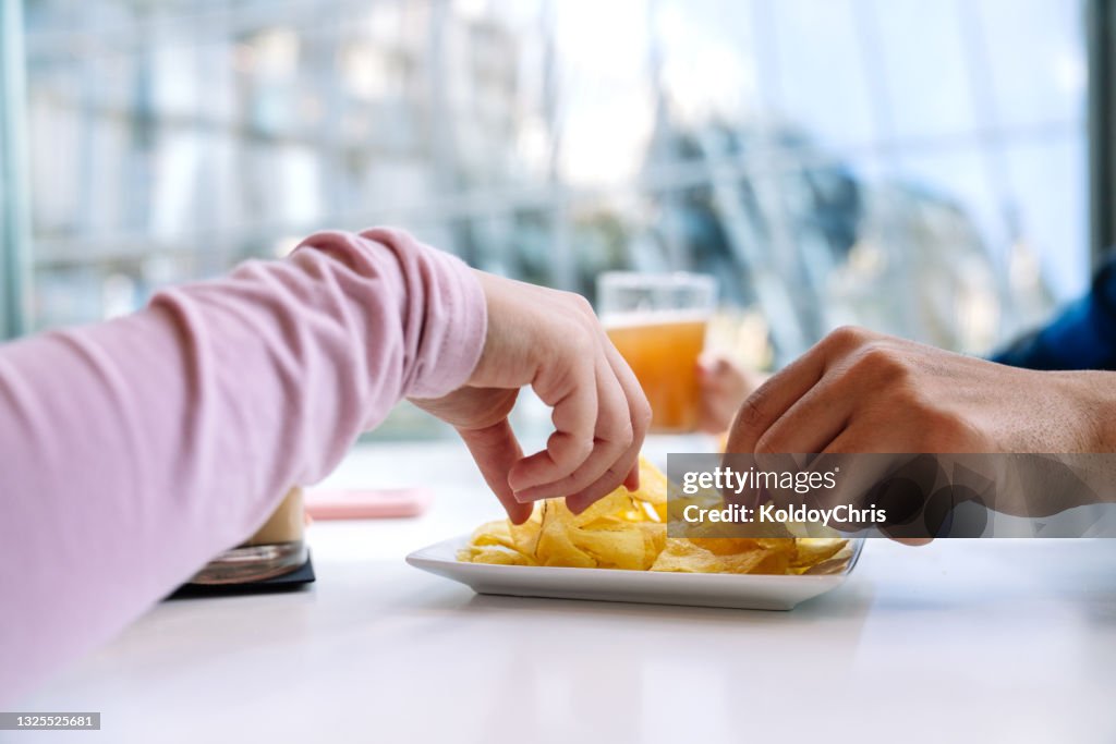 Close-up of the hands of some friends sharing potato chips in restaurant