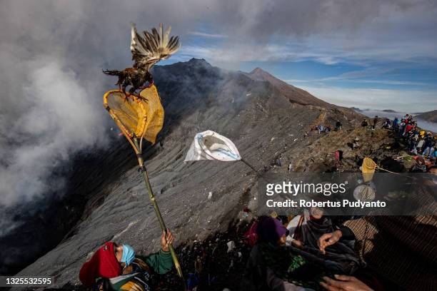 An Indonesian man catches a chicken thrown by Hindus Tenggerese worshippers at Mount Bromo during the Yadnya Kasada ritual on June 26, 2021 in...