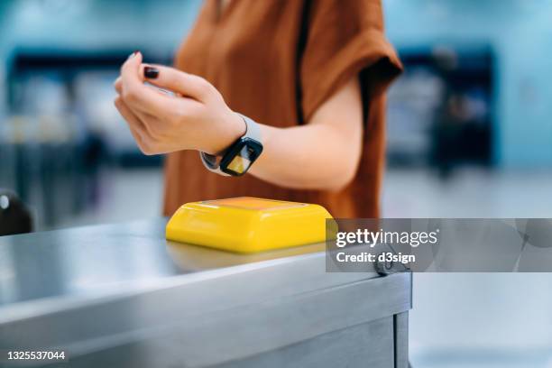 cropped shot of young asian woman checking in at subway station, making a quick and easy contactless payment for subway ticket via smartwatch. nfc technology, tap and go concept - reloj inteligente fotografías e imágenes de stock