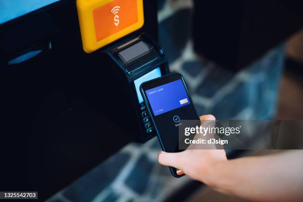 close up of a woman's hand paying with her smartphone on a vending machine, scan and pay a bill on a card machine making a quick and easy contactless payment. nfc technology, tap and go concept - nfc payment stock-fotos und bilder