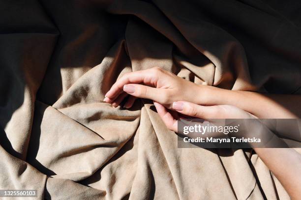 beautiful female hands with gentle manicure on a fabric background. - touching fabric stock pictures, royalty-free photos & images