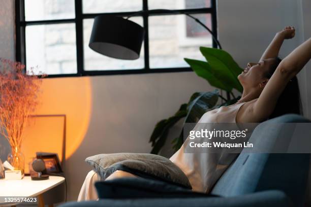 beautiful asian female sitting on the sofa with her hands up - human limb stock pictures, royalty-free photos & images