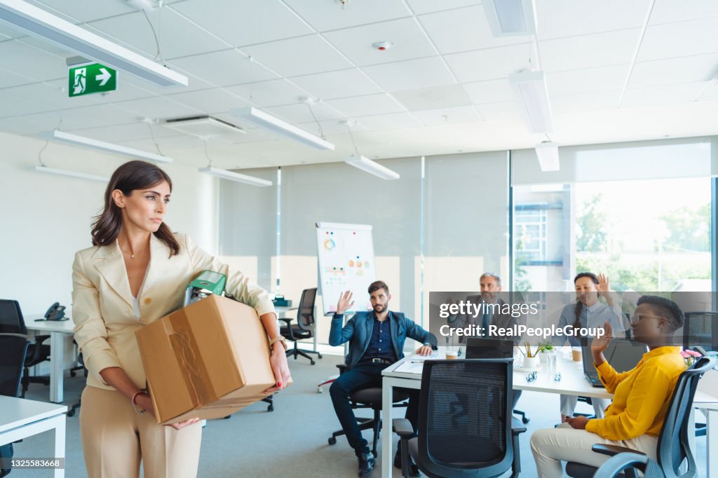 Shot of an unhappy businesswoman holding her box of belongings after getting fired from her job