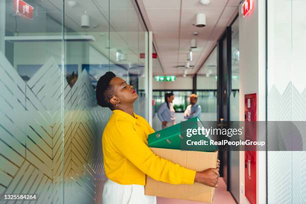 woman office worker is unhappy with being fired from a company packing things into cardboard boxes. - quitting a job stockfoto's en -beelden