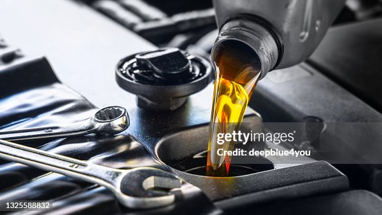 Pouring motor oil for motor vehicles from a gray bottle into the engine