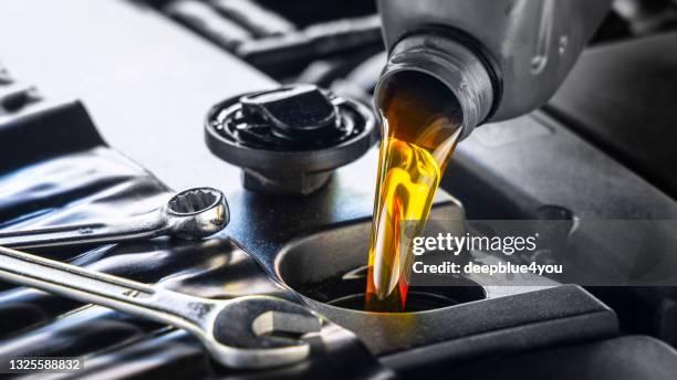 pouring motor oil for motor vehicles from a gray bottle into the engine - combustível fóssil imagens e fotografias de stock