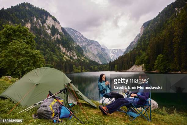 an adventurous young couple at their campsite and drinking coffee - camping couple stockfoto's en -beelden