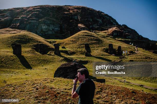 man from behind taking photos in the quarry where the moais were carved on the island of easter chile. - argentinien island stock pictures, royalty-free photos & images