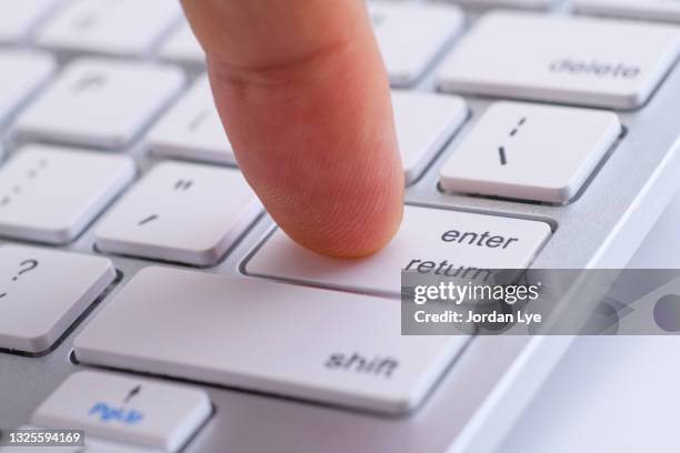 finger pressing enter button on computer keyboard - tecla enter fotografías e imágenes de stock