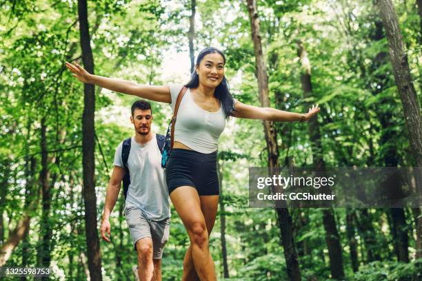 couple walking over a broken tree trunk in the forest - sportsperson stock pictures, royalty-free photos & images