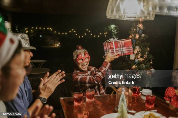 baby boomer woman satisfaction with gift for christmas and new year party at home - stock photo - funny christmas gift stockfoto's en -beelden