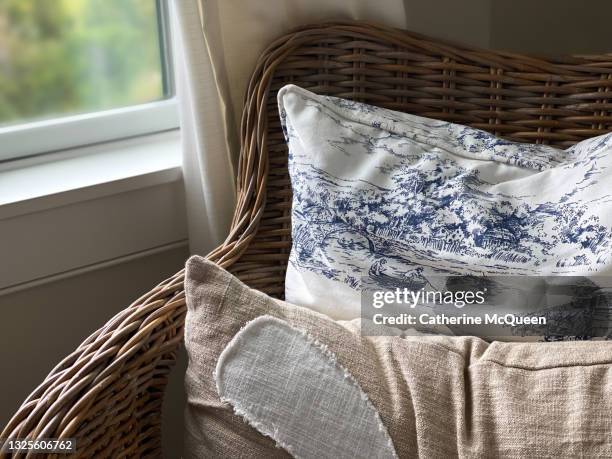 rattan wicker chair with throw pillows beside window with view of marsh - toile de jouy stock pictures, royalty-free photos & images