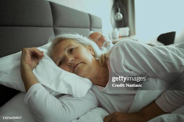 senior paar schlafen, senior frau mit schlafproblem - wife sleeping stock-fotos und bilder