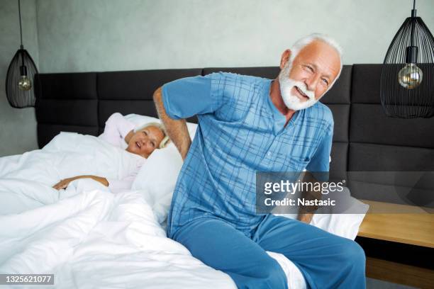 senior man is waking up with back pain - back pain bed stock pictures, royalty-free photos & images