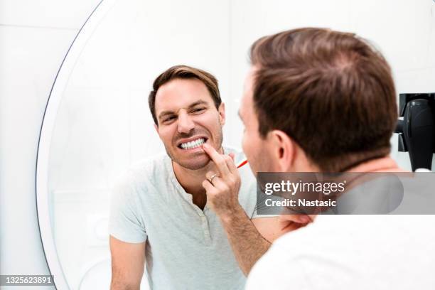 young man brushing teeth in the bathroom - mouth hygiene brush stock pictures, royalty-free photos & images