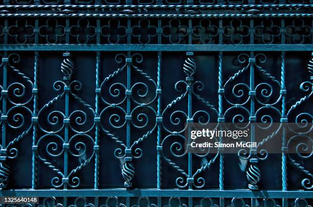 wrought iron metal gate with geometric pattern painted blue - hierro forjado fotografías e imágenes de stock