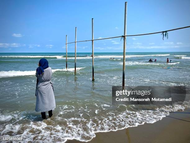 alone muslim woman next to the sea - muslim woman beach stock-fotos und bilder