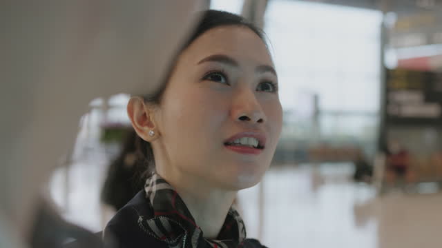 Close up of Young Chinese female cabin crew inform airplane arrival time to passenger - stock video