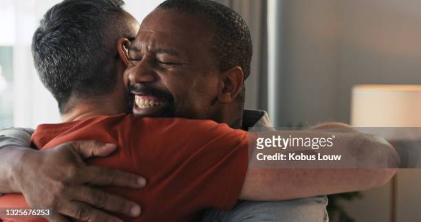 shot of two mature men embracing at home - apologize stockfoto's en -beelden