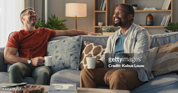 shot of two mature men having coffee and a chat on the sofa at home - 2 males stock pictures, royalty-free photos & images