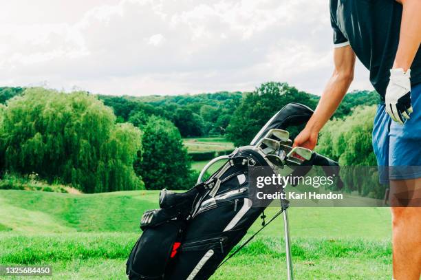 a daytime view of a golfer selecting a club - bolsa de golf fotografías e imágenes de stock